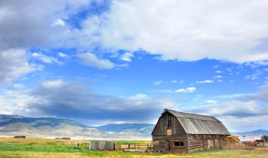 Cennet Vadisi 'ndeki kırsal kutup ambarı Gallatin Dağları' nın desteklediği güzel çayır arazisinde bulunuyor. Güzel sabah gökyüzü bulutlu ve canlı mavi.