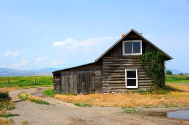 Çakıl yolu Happy Valley, Montana 'daki kır evi etrafında dönüyor. Galatin Dağları uzaklardan görülüyor.