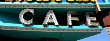 Kafe tabelası beyaz harfli turkuaz. Vintage işareti çoklu ampuller tarafından yakılır.