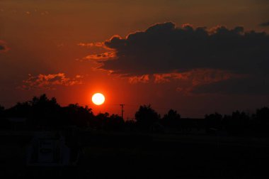 Güneş Bozeman, Montana 'da ağaçların arkasında batarken pembe ve turuncu gökyüzü kararır..