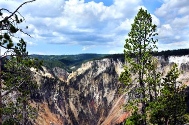 Yellowtone Ulusal Parkı 'ndaki Yukarı Şelale manzarası Yellowstone' un Büyük Kanyonu 'nun birçok rengi tarafından çerçevelenmiştir. Dik kanyon duvarları kahverengi, yeşil ve pembe renklidir..
