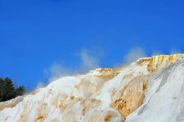 Upper Terrace, of the Mammoth Hot Springs in Yellowstone National Park, releases water vapor into the sky. clipart