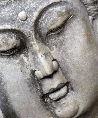 Meditasyon yapan Buddist kadın heykeli sakin bir yüz ve kapalı gözler gösteriyor. Heykelin yakın plan ve açılı görüntüsü.