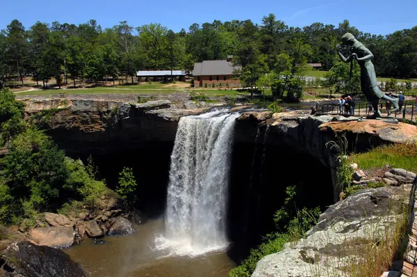 stock image Noccalula Falls is visited by tourists at the Nocalula Falls Park in the Appalachian Mountains.  Statue of Cherokee maiden is depicted running to jump over the falls.