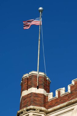 Canlı mavi gökyüzü Hot Springs, Arkansas 'taki eski Hot Springs Lisesi binasının üzerinde dalgalanan Amerikan bayrağını çerçeveledi. Bu bina Başkan Bill Clinton 'ın mezun olduğu okul..