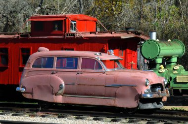 Vintage railcar rides the rails at a railroad yard in Northern Arkansas.  Red caboose sits behind it clipart