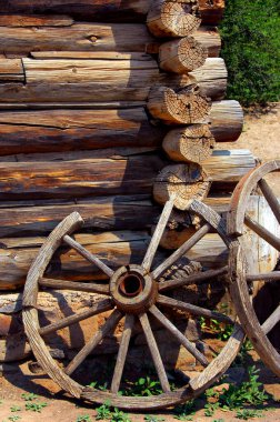 El Rancho De Las Golondrinas Ulusal Tarihi Patikası 'nda iki kırsal vagon tekeri bir kulübe duvarına yaslanıyor..