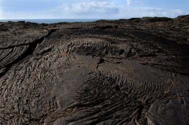 Hawaii Volkanik Ulusal Parkı, Kilauea 'nın sürekli okyanusa akışı nedeniyle her yıl yeni bir kara parçasına sahiptir. Bu lav alanı Büyük Adalar 'ın kütlesine yakın zamanda eklendi. Arkaplan resmi.