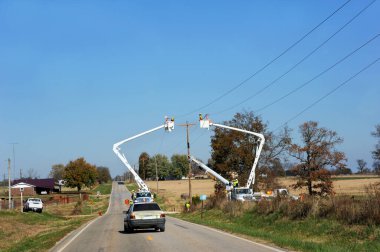 Arkansas kırsalında telefon hatlarında çalışan iki hat çalışanı vişne toplayıcıları arasında duruyor. Araç ekipmanın etrafından dolaşmak için yavaşladı..