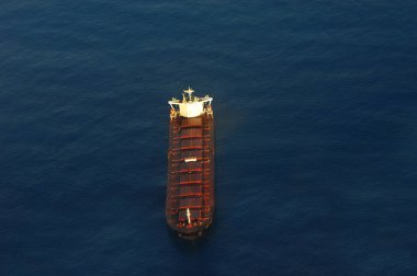 Yük gemisi, Mamala Körfezi 'nin koyu mavi sularını Honolulu, Hawaii' ye yanaştırıyor. Sabahın erken saatleri kargo gemisinin güneş ışığını yakalamasına neden olur..