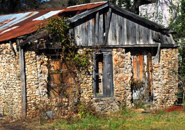 Kuzey Arkansas 'ta bir taş ev bakımsız, terk edilmiş ve büyümüş bir halde duruyor. Tahtalar kırıldı ve çatı paslanıyor..