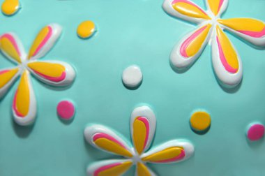 Üç boyutlu çiçekler ve benekli noktalar bir turkuaz yüzeyde bulunur. Yüzey biraz eğri..