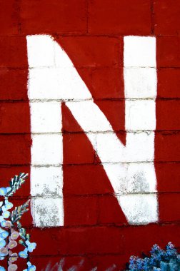 N harfi bordo bir zemin üzerine boyanmış ve çiçeklerle süslenmiş..