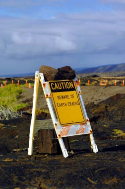 Sign is secured with lava rocks.  White folding sign with yellow caution sign attached stating 