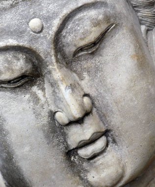Meditasyon yapan Buddist kadın heykeli sakin bir yüz ve kapalı gözler gösteriyor. Heykelin yakın plan ve açılı görüntüsü.