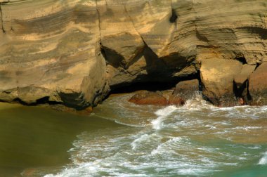 Secluded Green Sand Beach is a tourist destination on the Big Island of Hawaii.   Towering cliff has been eroded by wind and waves. clipart