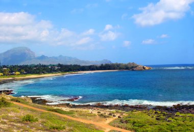 Beautiful Keoneloa Bay front resort and rocky Makahuena Point protects Shipwreck Beach on the Island of Kauai, Hawaii. clipart