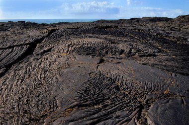 Hawaii Volkanik Ulusal Parkı, Kilauea 'nın sürekli okyanusa akışı nedeniyle her yıl yeni bir kara parçasına sahiptir. Bu lav alanı Büyük Adalar 'ın kütlesine yakın zamanda eklendi. Arkaplan resmi.