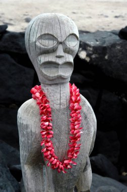 Fresh plumeria lei hangs from the neck of an ancient tiki at Puuhonua o Honaunau National Historical Park on the Big Island of Hawaii. clipart