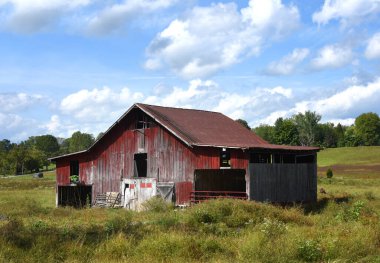 Kırmızı ahşap ahır yıpranmış ve solmuş. Tennessee kırsalında yer alır. Ön taraftaki çift kapılar da soluk beyaz. Mavi gökyüzü güneşli..