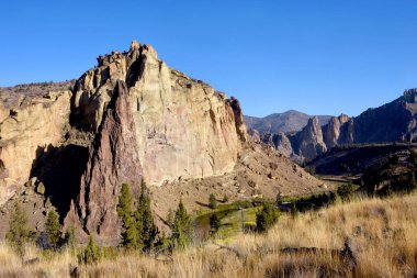 Sabah güneşi Oregon 'daki Smith Rock State Parkı' nın uçurumlarına vurgu yapıyor. Eğri Nehir üsten akıyor..