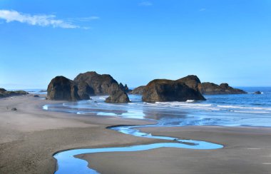 Su, Myers Sahili 'nin kuzeyindeki Pasifik Okyanusu' na akar. 101. Otoyol 'da, Oregon' da. Görkemli deniz yığınları sahilde oturur..