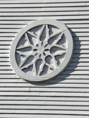 Beyaz ahşap daire veya tekerlek Waterbury, Vermont 'taki Beyaz Saray Birleşik İsa Kilisesi' ne monte edilmiştir. Amblem kaba ve pürüzlü..