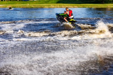 Bir adam jet ski ile nehirde yüzüyor.