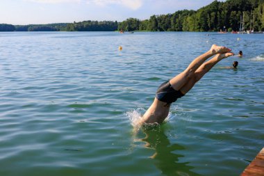 Adamın biri iskeleden göle atlıyor. Düz bacaklar