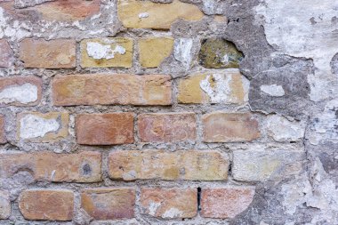 Eski tuğla bir duvar alçı kalıntılarıyla döşenmiş. Kırmızı ve sarı tuğlalar.