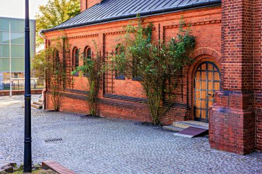 Kilisenin tuğla duvarı, kemerli bir kapı ve gül ağacı çalıları. Yüksek kalite fotoğraf