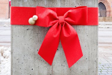 Beton bir sütunun etrafında Noel topları olan büyük kırmızı bir fiyonk şeklinde dekorasyon. Yüksek kalite fotoğraf