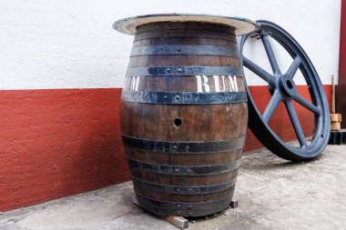 Metal halkalı eski ahşap fıçı ve romlu. Fıçı ve büyük bir tekerlek kırmızı ve beyaz bir duvara karşı. Yüksek kalite fotoğraf