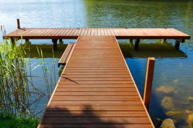 Küçük bir gölün kıyısında güçlü, ahşap bir köprü. Sazlıklar köprünün yanında. Yüksek kalite fotoğraf