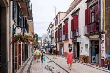 Funchal, Portekiz 8 Temmuz 2025, eski kentin dar yaya sokağı turistlerle dolanıyor. Pencere panjurlarını aç. Yüksek kalite fotoğraf