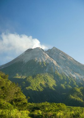 Merapi Yogyakarta Endonezya 'da mavi gökyüzü ile güzel dağ ve yeşil orman