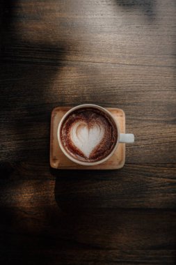 Kahve latte sanatı. Tahta masada kalp şeklinde sıcak kahve.