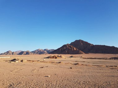 Kumlu genişlikleri ve görkemli kayalık dağlarıyla Mısır 'ın etkileyici manzarası. Güneş ışınları kum ve kayalık yamaçların dokusunu vurgular. Seyahat kavramları, tarihi temalar veya çöl estetiği için