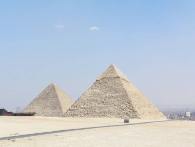 Uzakta, Mısır 'ın görkemli piramitleri sonsuz çölün ve parlak mavi gökyüzünün arka planına karşı görünür. Firavunların antik mezarları, tarihin gizemleriyle örtülüydü.