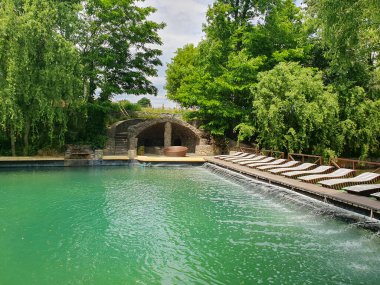 Taze yeşil çimenler ve uzun ağaçlarla çevrili yaz havuzu. Sıcak mevsimde dinlenmek ve dinlenmek için bir yer. Reklam merkezleri, oteller veya yaz tatili için uygun.