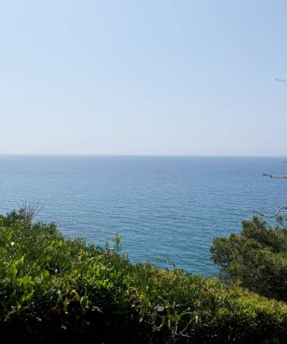 Sonsuz mavi deniz manzarası ve parlak bir yaz gününde görkemli dağlar. Güneş ışınları su yüzeyinde, gölgelerin derinliğini vurguluyor. Özgürlüğün, maceranın atmosferini taşır