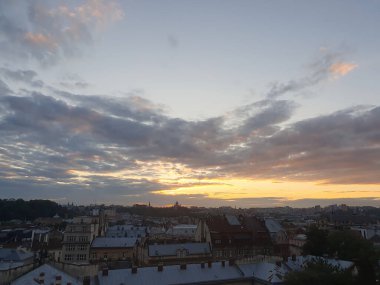 Şehrin üzerinde destansı bir yaz akşamı günbatımı. Gökyüzü parlak turuncu ve pembe renkte parlak bir paletle kaplıdır. Güneşin son ışınları ufukta kayboluyor..
