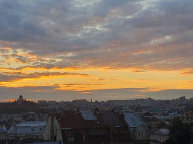 Şehrin üzerinde destansı bir yaz akşamı günbatımı. Gökyüzü parlak turuncu ve pembe renkte parlak bir paletle kaplıdır. Güneşin son ışınları ufukta kayboluyor..
