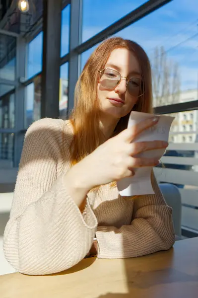 Görüntü, bir kafede iyi aydınlatılmış bir masada oturan bir adamın makbuzuna baktığını gösteriyor..