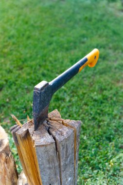 Bulanık yeşil çimen arka plan karşı bir günlük gömülü bir balta, insan yapımı araç ve doğal elementler arasındaki kontrastı vurguluyor