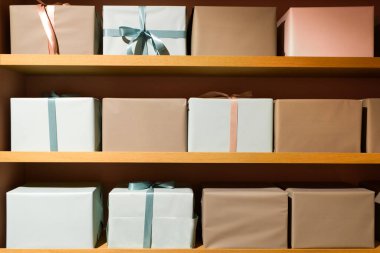 The image features beautifully wrapped gift boxes in pastel colors, neatly arranged on wooden shelves.  clipart