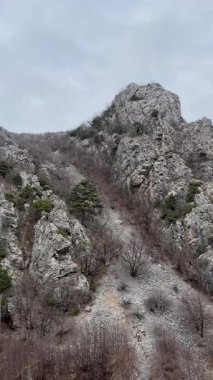 Senjska Draga 'da kayalık uçurumlar, seyrek bitki örtüsü ve HDR' de yakalanan bulutlu bir gökyüzü içeren engebeli bir dağ manzarası. Sahne dingin ve doğal güzellikleri gösteriyor..