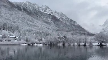 Karla kaplı dağlar ve ağaçların yer aldığı sakin bir kış manzarası Jasna 'da yakalanan bulutlu bir gökyüzünün altında sakin bir göle yansıdı.