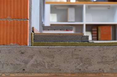 Binanın termal yalıtımının yakın görüntüsü tuğla, beton ve yalıtım malzemelerinin katmanlarını gösteriyor..