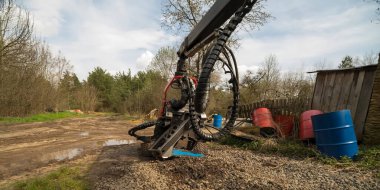  Ormandaki ağaçları kemiren makine başı. Ağaç temizleme. Makine çiftlikte park halinde. Görünür çelik variller, uzaktaki orman ve tarlalar. 